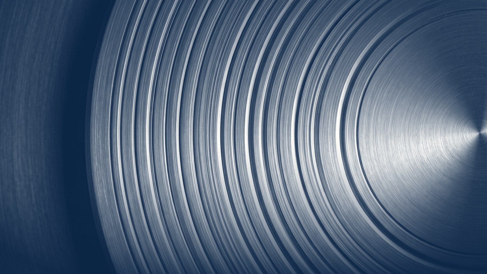 Concentric grooves in brushed metal radiating from a bright centre, toned navy